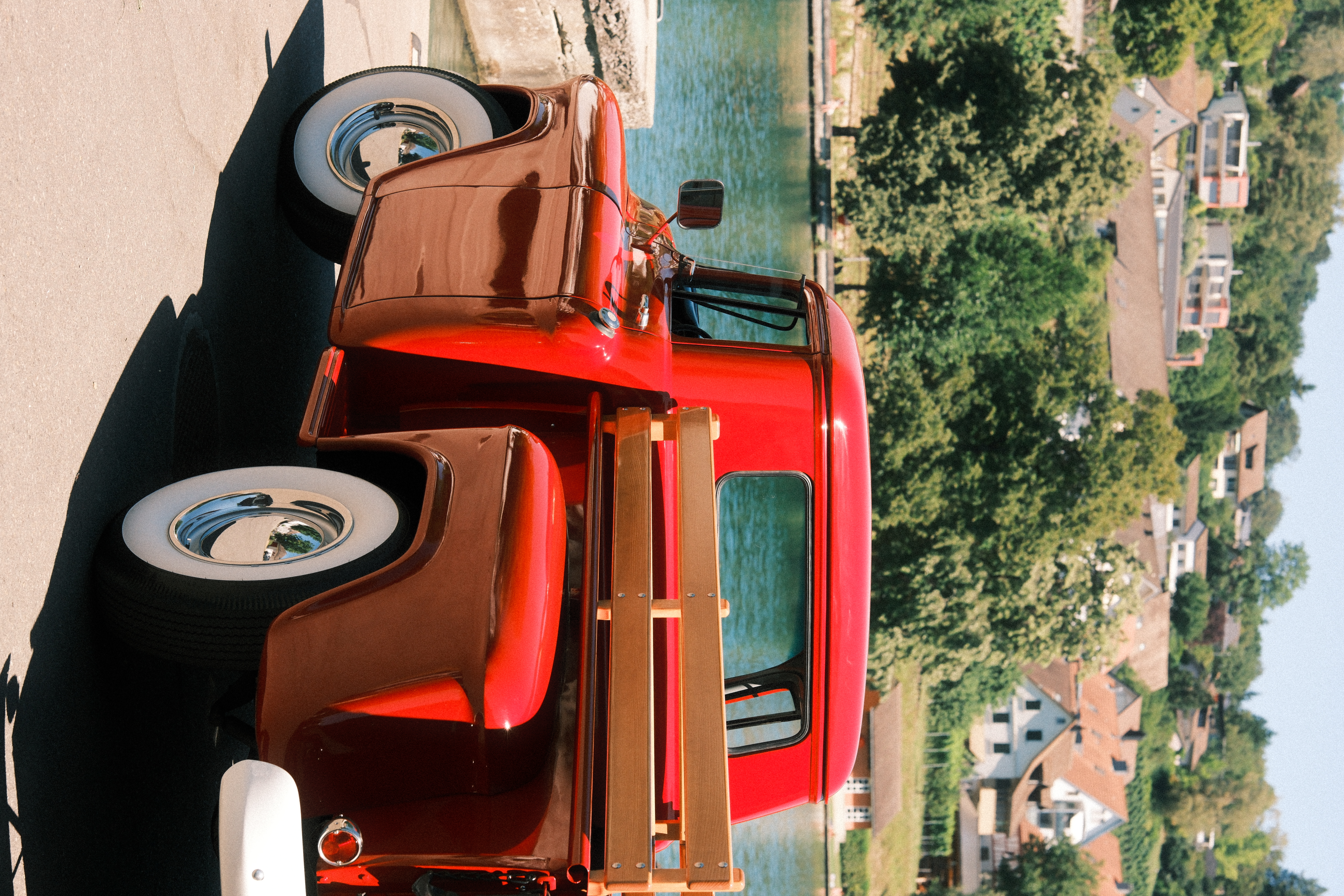 Roter Chevy Pickup von hinten am Seeufer vor Dorfkulisse